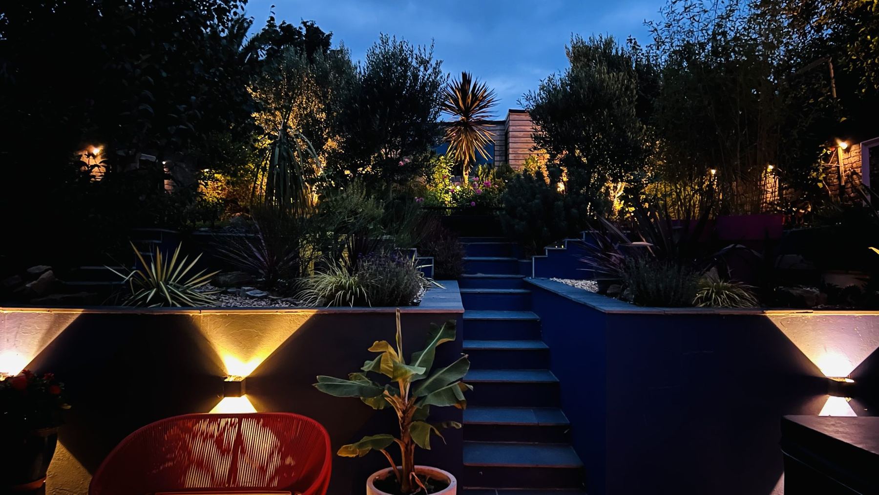 The studio garden at dusk, lit terraces and steps